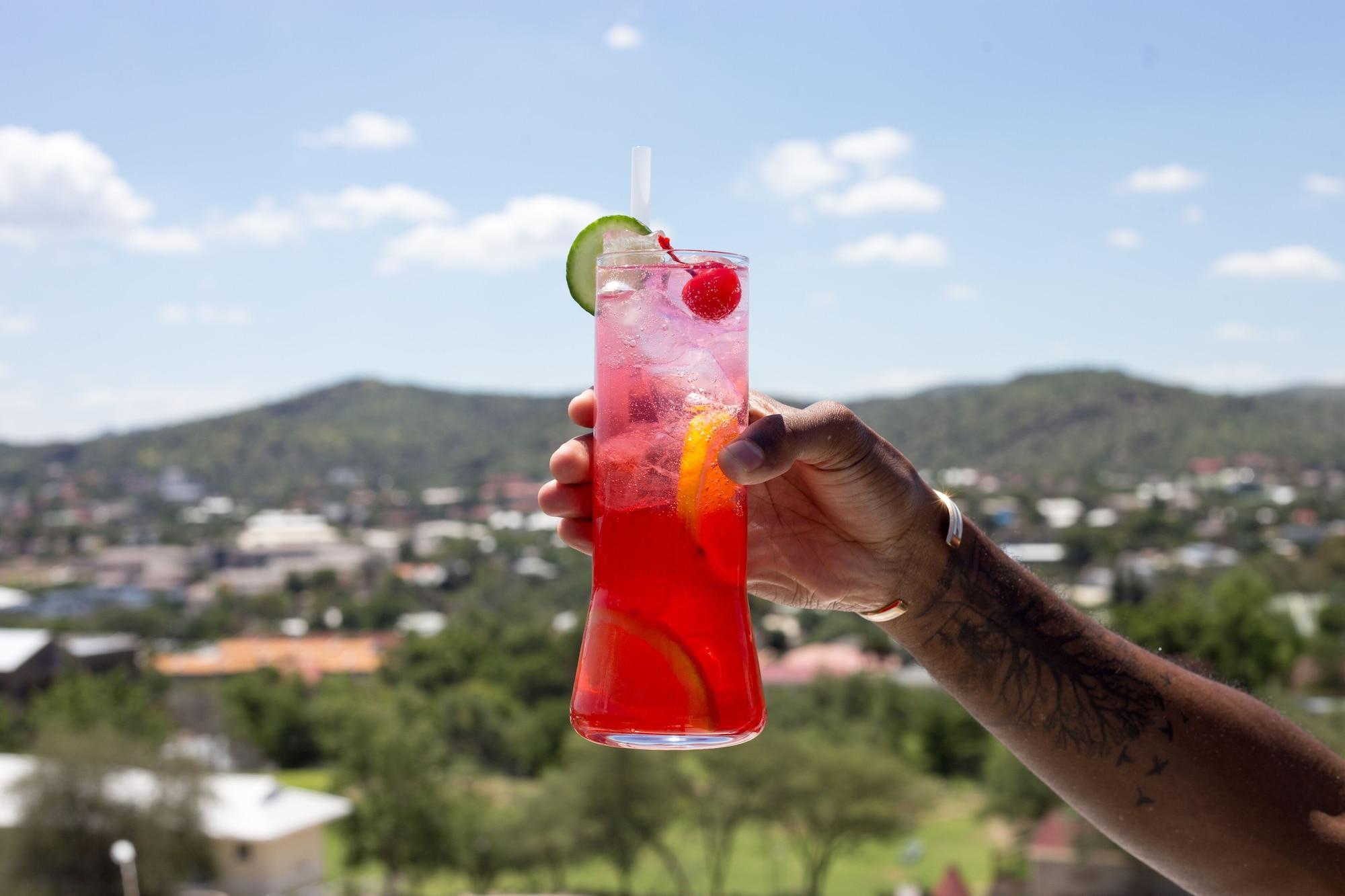 The Weinberg ווינדהוק מראה חיצוני תמונה A hand holding a glass of a fruit punch